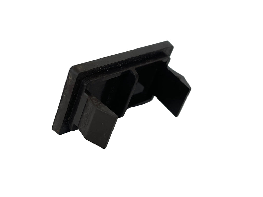 A small black plastic clip or fastener component photographed on a plain light surface.