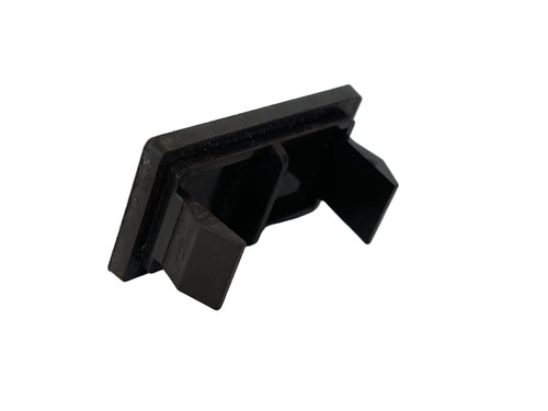 A small black plastic clip or fastener component photographed on a plain light surface.
