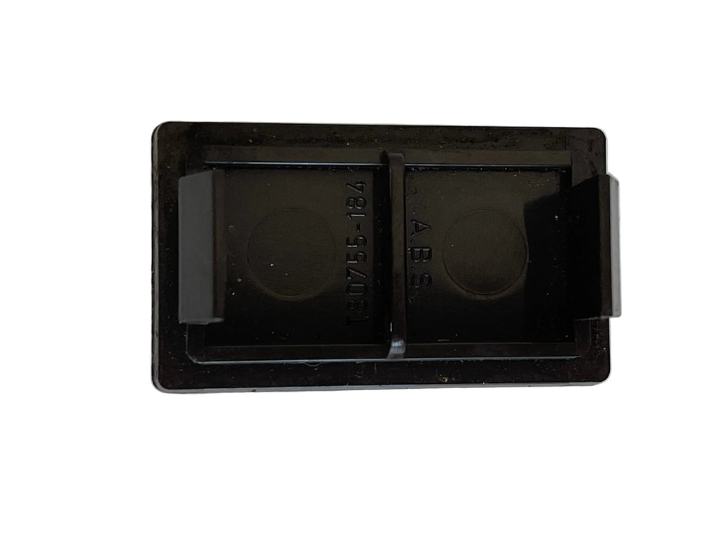 A black plastic double-bayonet clip, likely a camera lens accessory, shown from above on a light off-white textured surface.