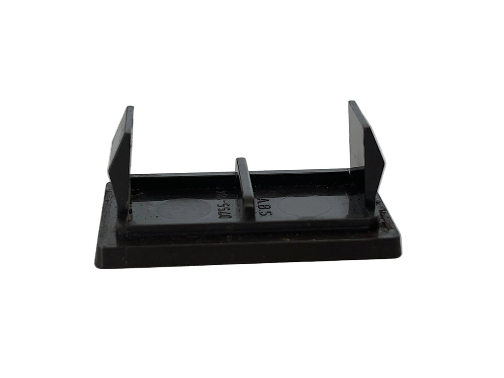 A small black plastic or metal bracket-like component with a rectangular base, two upright angled arms, and a short center tab, photographed on a light off-white surface.