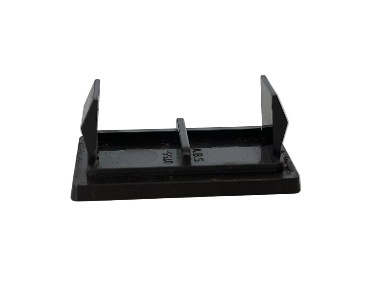 A small black plastic or metal bracket-like component with a rectangular base, two upright angled arms, and a short center tab, photographed on a light off-white surface.